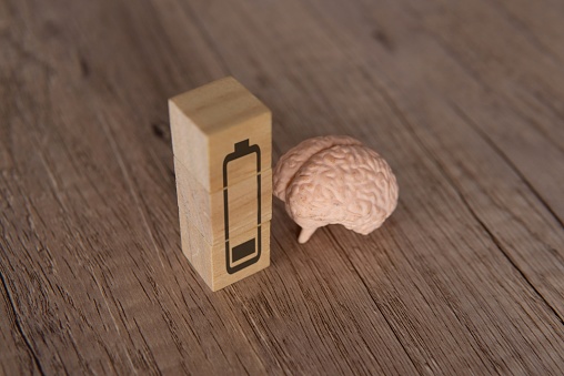 Closeup image of brain and wooden blocks with low energy battery icon. Exhausted, tired and burnout concept.