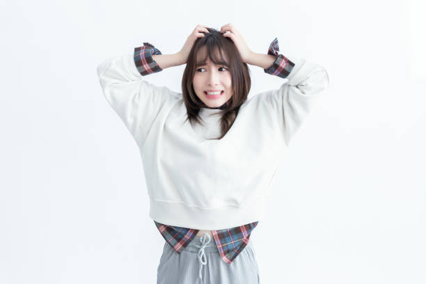 不安げな若い女性が頭を抱えている - うつ病 日本人 ストックフォトと画像