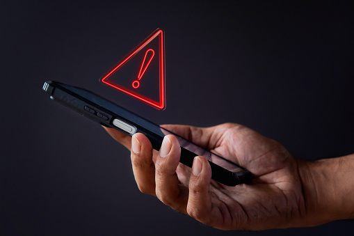 Smartphone with triangle caution warning icon. System error, malware and cyber crime concept.
