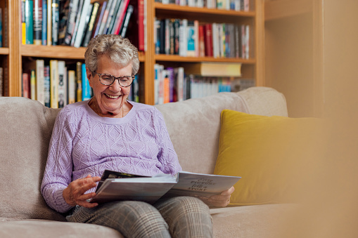 A senior woman sitting on a sofa at home in Seghill, Northumberland. She has dementia and is spending time looking through a photo album to aid her memory and remind her of the relationships she has with people in the book.

Videos also available for similar scenario.