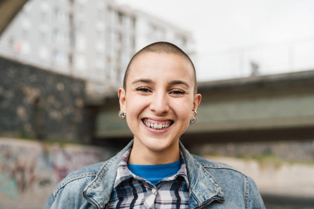 istock Happy young woman with shaved head smiling in front of camera 1909431007