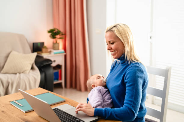 Happy mother using laptop while her small baby is sleeping