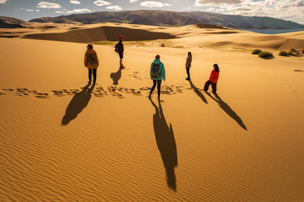 un grupo de turistas está de pie en las dunas de la puesta del sol - gobi desert fotografías e imágenes de stock