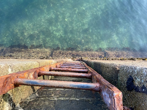 An aged metal ladder on the edge of turquoise waters