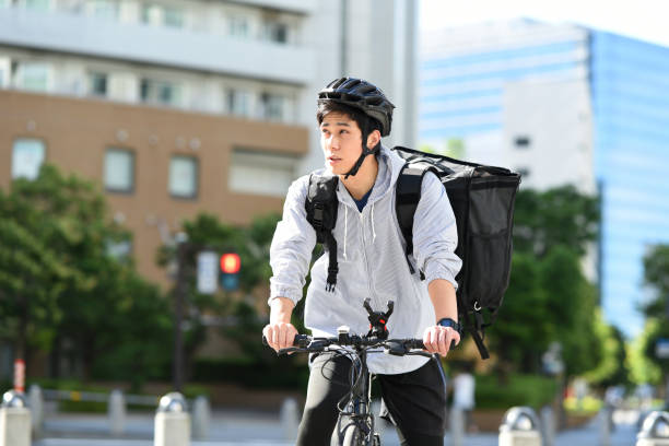 istock Young Asian man with backpack and providing delivery service on bicycle 1909495621