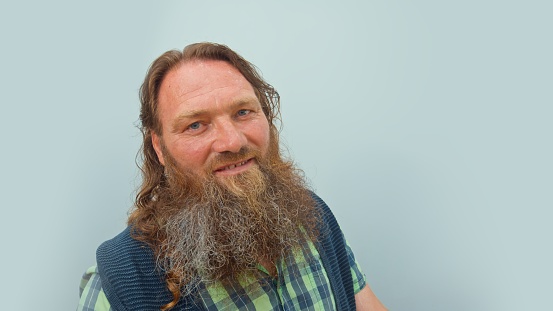 Man with a red beard and long hair smiling looking at camera