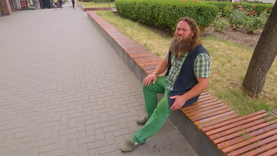 Long-bearded elderly man sitting alone on a park bench