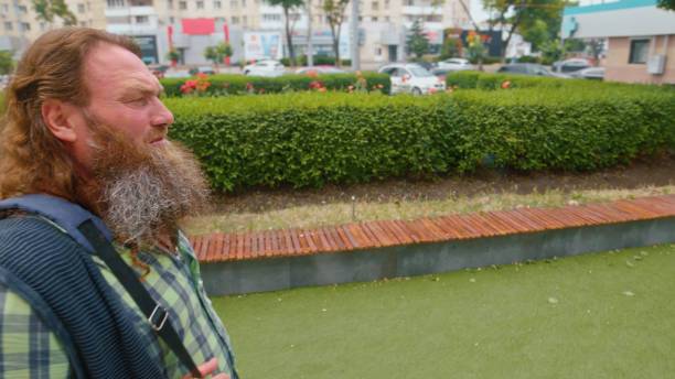 An elderly man is sitting on a bench in a public park