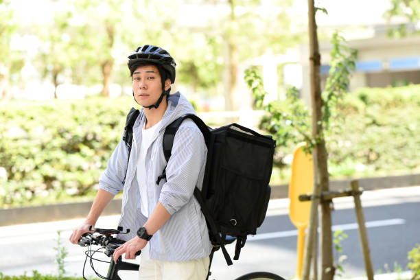 istock Young Asian man with backpack and providing delivery service on bicycle 1909504595