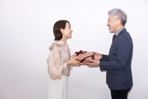 A woman is giving a present to a man.