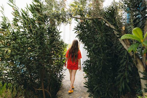 4k video footage of female with long hair in orange dress walking in the beautiful garden with natural arch in Mediterranean Turkey