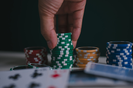 a man or poker player stack chips on table in concept of casino gambling all in