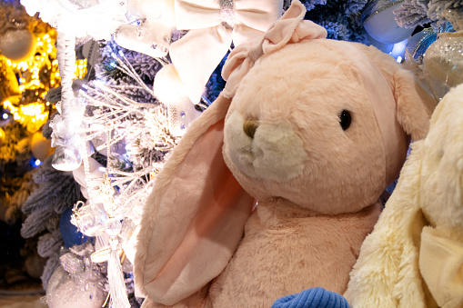 Plush toy bunnies on the background of a Christmas tree.