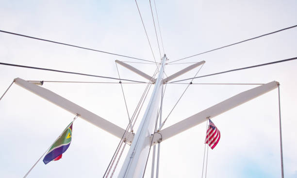 mast einer segelyacht ohne segel. unteransicht auf einem hintergrund des blauen himmels mit wolken. - repairing sky luxury boat deck stock-fotos und bilder