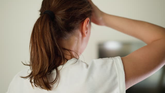 Tired woman strokes head standing in room closeup