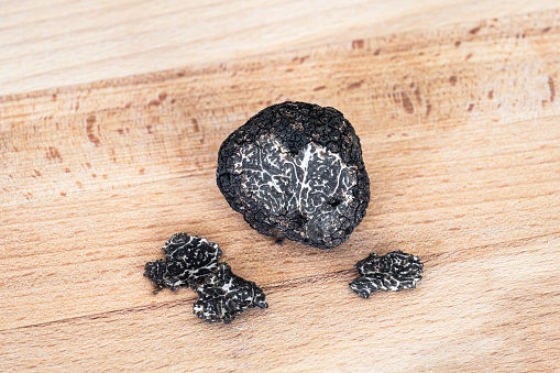 Close-up on a black edible winter truffle, on wooden background