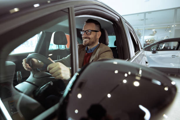 istock Smiling man admiring new car in a showroom 1909623633