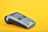 Payment terminal, compact POS terminal on yellow background top view copy space.