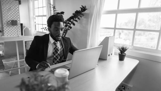 Business African man doing online video conference on laptop inside modern office - Black and white editing