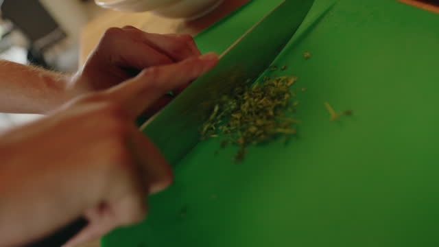 Close-up hands of man cutting parsley  in the kitchen