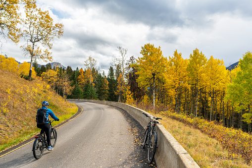 Tourist cycling on the Bow Valley Parkway in fall foliage season. Banff National Park, Canadian Rockies, Alberta, Canada.