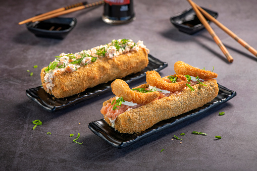Shrimp and Salmon fried sushi shaped as hotdog on grey background.
