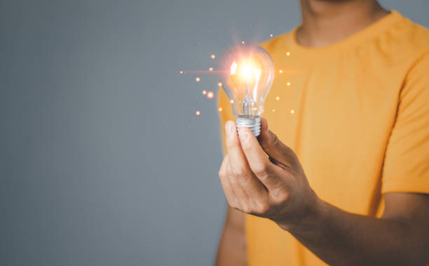 istock Idea innovation and inspiration concept. Hand of man holding illuminated light bulb, concept creativity with bulbs that shine glitter. Inspiration of ideas for sustainable business development. 1909679507