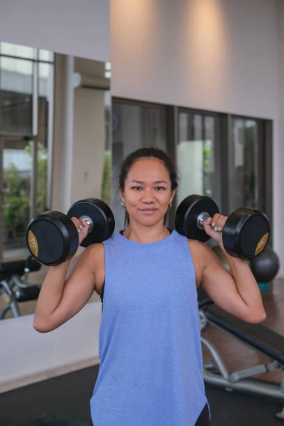 istock Asian Woman Lifting Two Dumbbell on Her Shoulder 1909696077