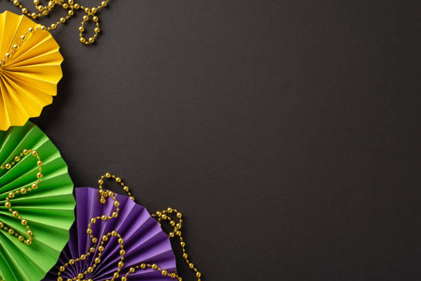 istock Grand Masquerade Elements: Overhead view of extravagant bead string, and colorful paper fans set against a dark background, offering an open canvas for text or promotional content 1909720865