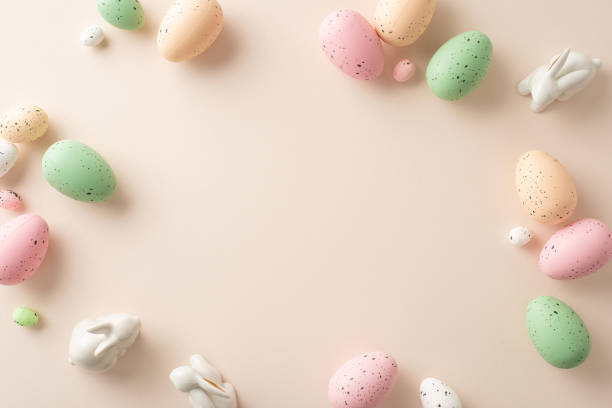 istock Easter charm arrangement unfolds in this top-view snapshot. Classic quail eggs, a sweet ceramic bunnies on a pastel beige canvas with frame for your text or promotion 1909720871
