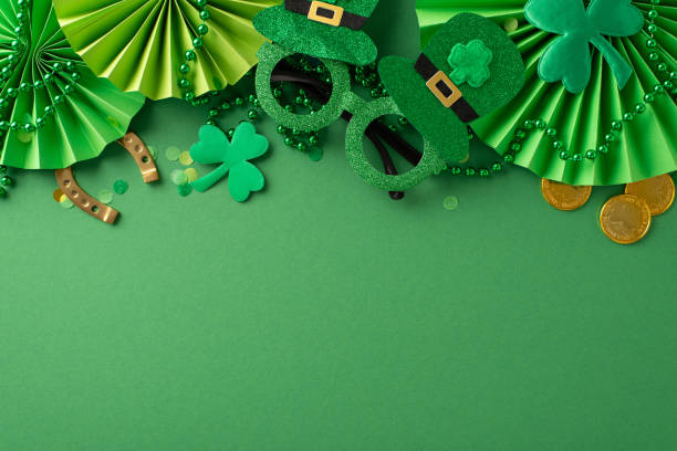 istock Capture essence of Saint Patrick's Day with top view flat lay featuring iconic elements: playful party glasses, golden coins, excited fans, shamrocks, confetti on green canvas. Advertise in open space 1909720877