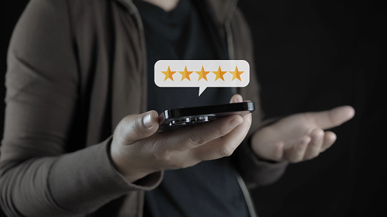 customer man hand pressing on smartphone screen with gold five star rating feedback icon and press level excellent rank for giving best score point to review the service