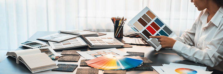 Interior architect designer at workstation table choosing various color samples art tool design with home blueprint. Creative color selection for house renovation or design concept. Insight