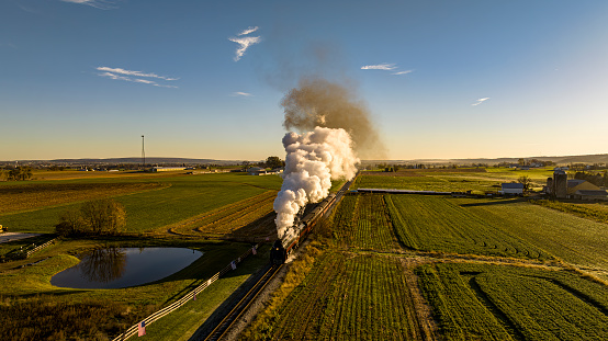 A vintage steam locomotive on a journey through a peaceful countryside landscape. USA