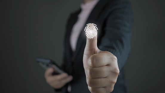 Service users lift their thumbs up and scan their fingers to enter the identity verification system. There is a fingerprint scanning light icon. Security concept for accessing technology systems.