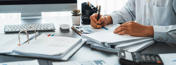 Corporate auditor calculating budget with calculator on his office desk. Insight