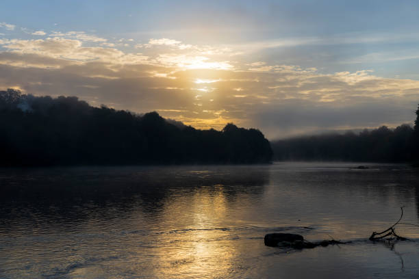 Morning fog on the surface of the river, autumn nature with the river and trees on the river bank