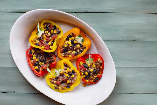 Overhead view of vegan stuffed peppers. These bell peppers have been filled with a southwestern mix of quinoa, corn, black beans, tomatoes and herbs. High in fiber and delicious. Top view.