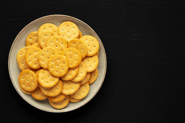 istock Salty Round Crackers on a Plate on a black surface, top view. Flat lay, overhead, from above. Copy space. 1909957031