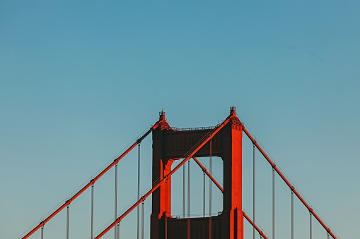 Close-up of top of the tower of famous iconic Golden Gate Bridge over the blue sky, California, USA