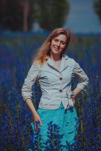 Portrait of beautiful elegant woman in a blue flower meadow