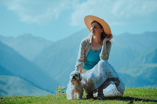Beautiful elegant woman with shih tzu dog on mountain background