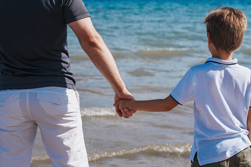 Father and son standing on the beach holding hands