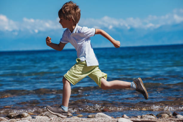 istock Boy running on the lake shore at sunny day 1909977041
