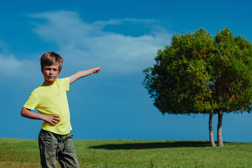 Boy points to the tree on a sunny day, ecology concept