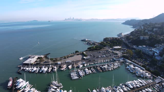 Drone captures the bustling Sausalito marina with a stunning backdrop of the iconic San Francisco cityscape and Bay Bridge.