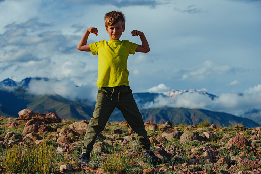 Happy strong boy on mountains background in summer