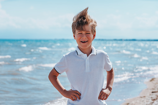 Portait of a young boy standing in a field while at a farm in Autumn, smiling while looking at the camera.