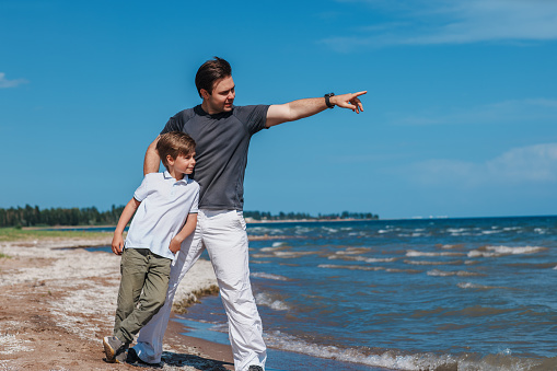 Father and son standing on shore of the lake and looking away