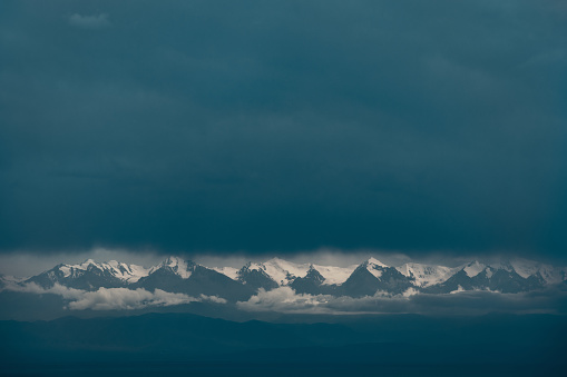 Picturesque dramatic landscape of snow-covered mountain tops amidst clouds and fog